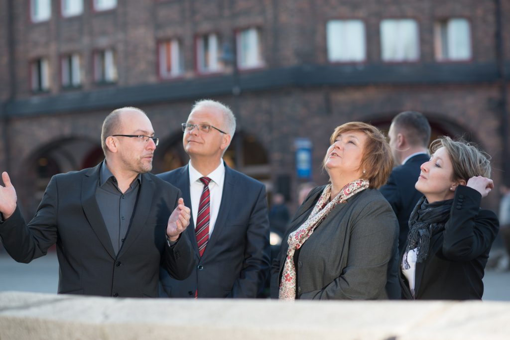 Anna Komorowska i Piotr Litwa wraz z przewodnikami oglądają detale architektoniczne zabytkowej dzielnicy Katowic.