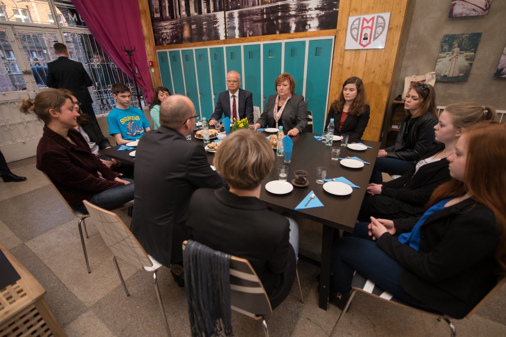 Uczestnicy spotkania w Centrum Zimbardo. Osoby siedzą przy stole, kolejne ujęcie.