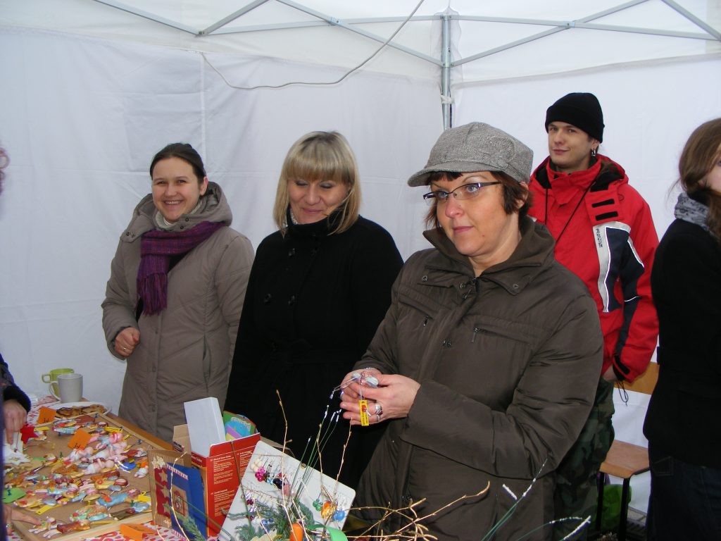 Kilka os&oacute;b przy stoisku, na stole leżą kolorowe ozdoby.