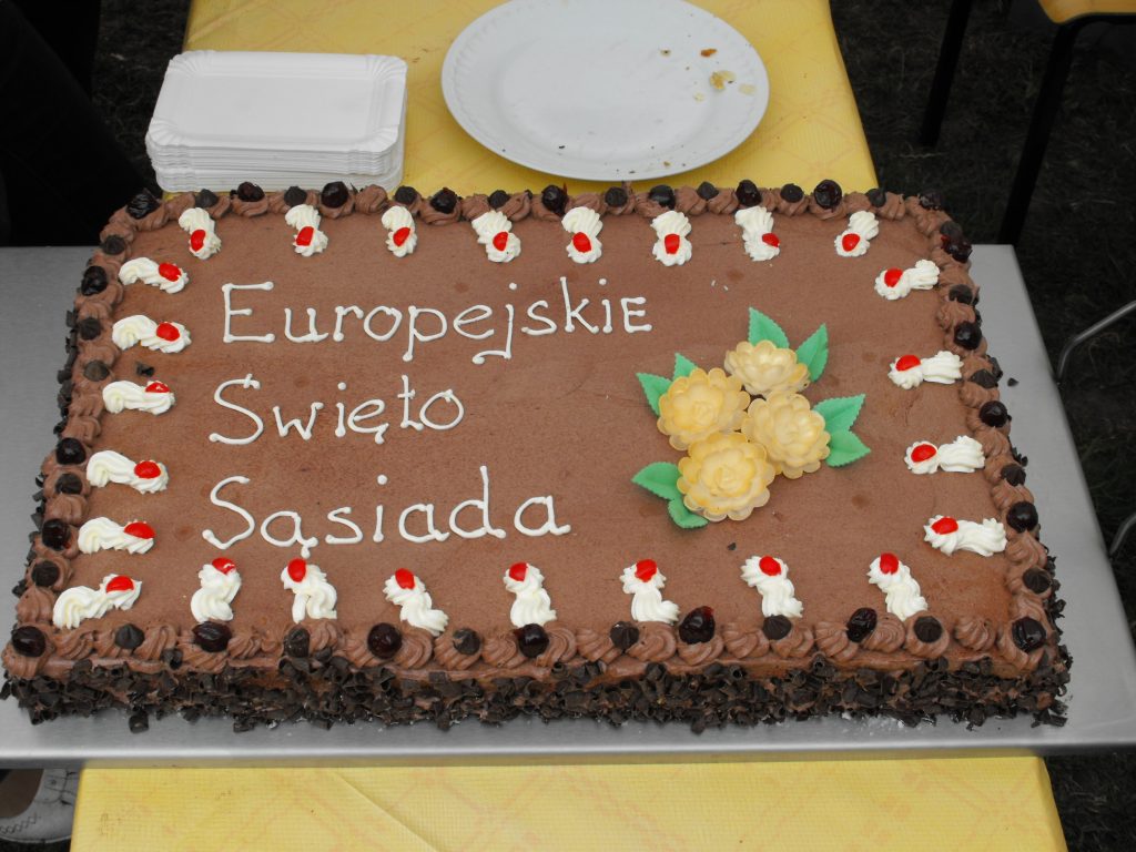 Tort czekoladowy z białym napisem Europejskie święto sąsiada.