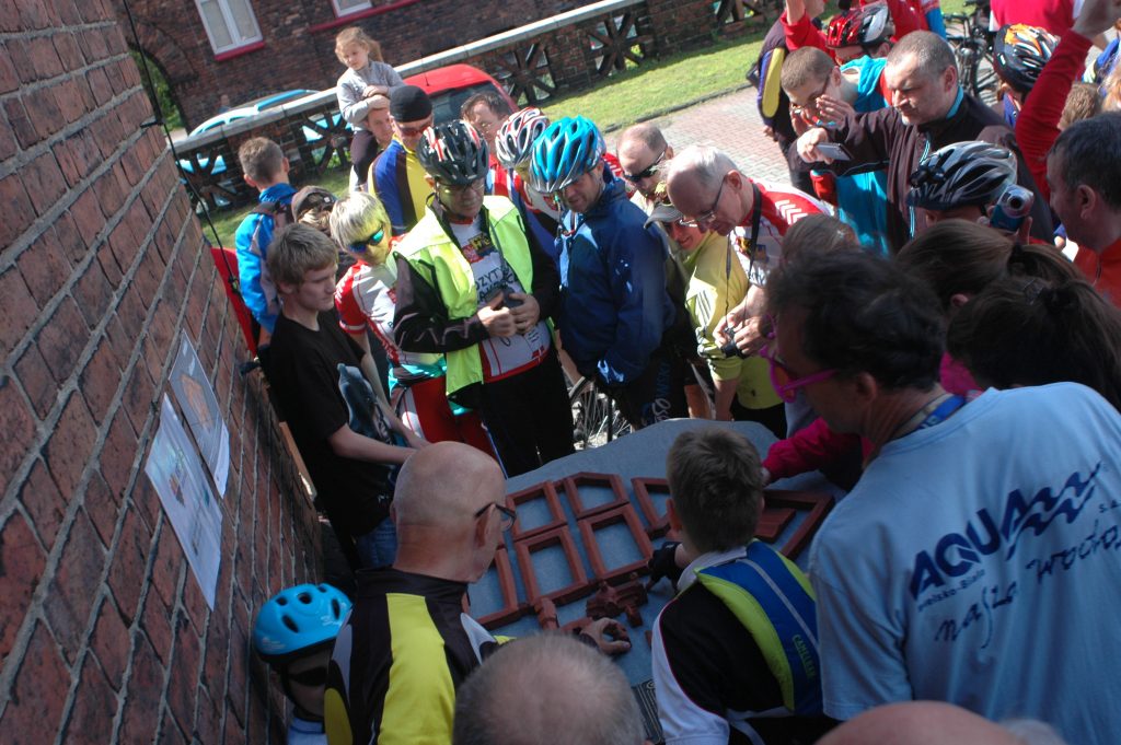 Widok z g&oacute;ry na grupę rowerzyst&oacute;w oglądających makietę Nikiszowca.