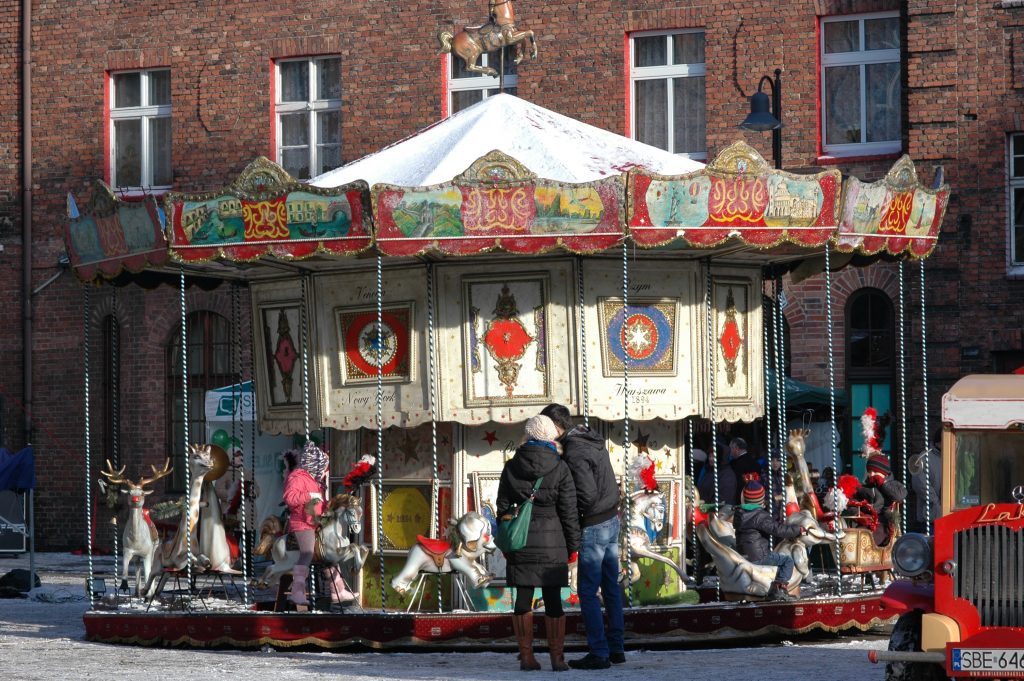 Dwie osoby stoją przed zabytkową karuzelą.