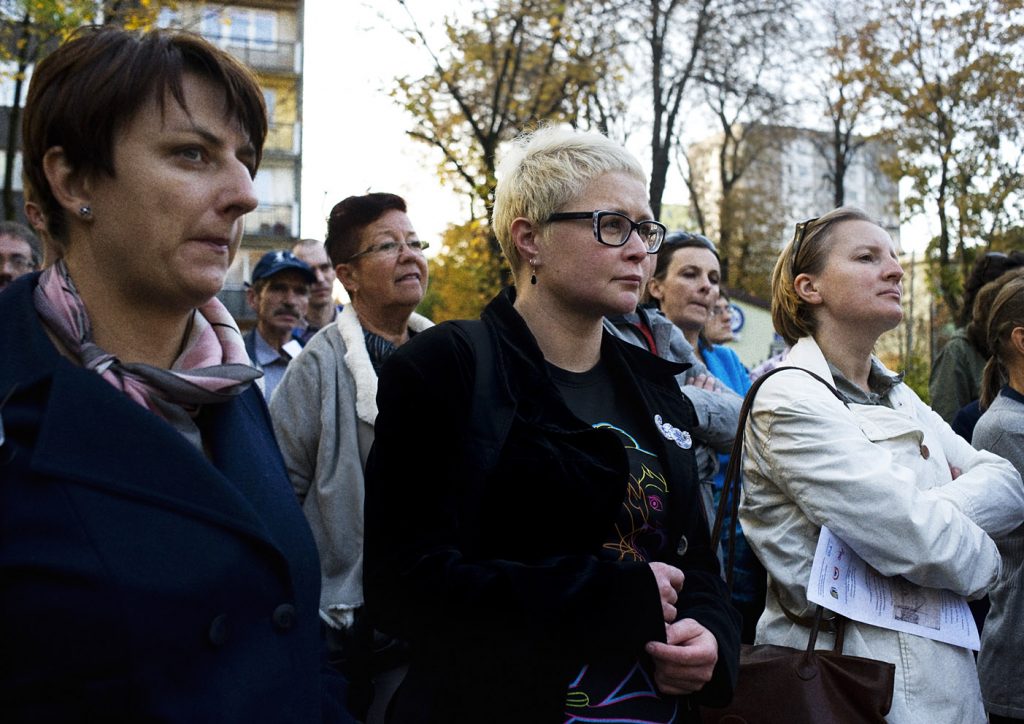Grupa kobiet ze skupieniem na twarzy stoi na zewnątrz w jesienny dzień.