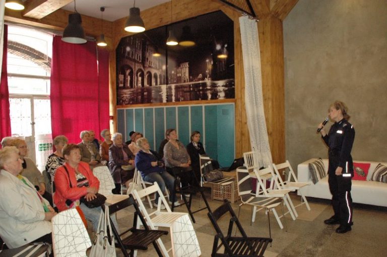 Grupa seniorek w trakcie pogadanki z policjantką.