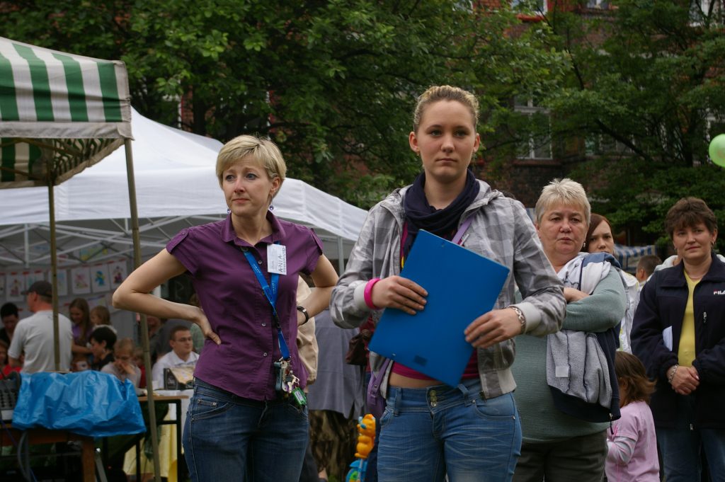 Dwie kobiety stojące na plenerowym wydarzeniu. W tle piknikowe namioty i inni uczestnicy.